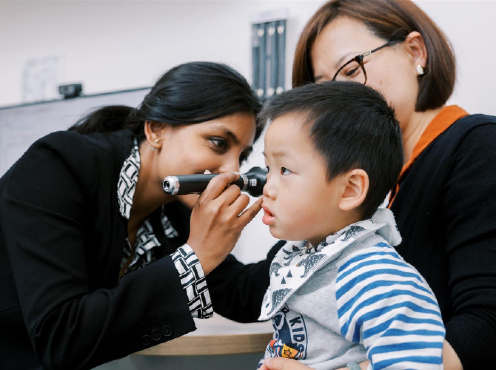 Healthcare practitioner examining a young boy’s ear during a paediatric consultation